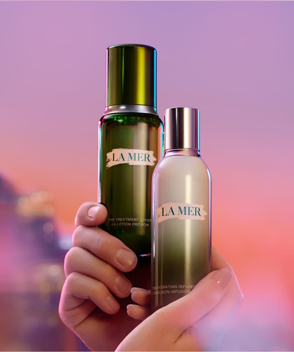Selection of La Mer bestselling, held by hands, pink and purple backround
