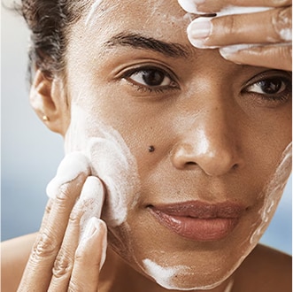 Close up of model cleansing skin, focusing on product texture on skin